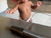Baby Playing with Vacuum Puts Hose to Face