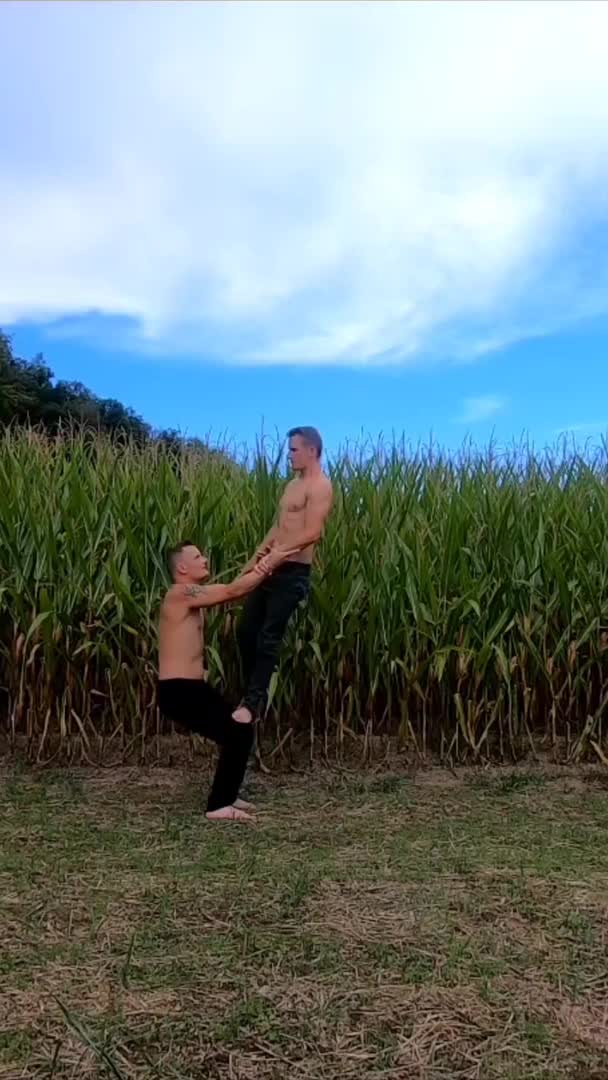 Duo Attempts Balancing Act in Front of Field