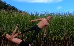 Duo Attempts Balancing Act in Front of Field