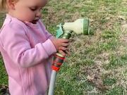 Daughter Sprinkles Water on Dad With Hose
