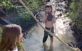 Boy Licks Rock After Picking It Up from Creek