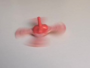 Whirling a Red Humming Top in Slow Motion