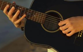A man playing guitar near water - Music - VIDEOTIME.COM
